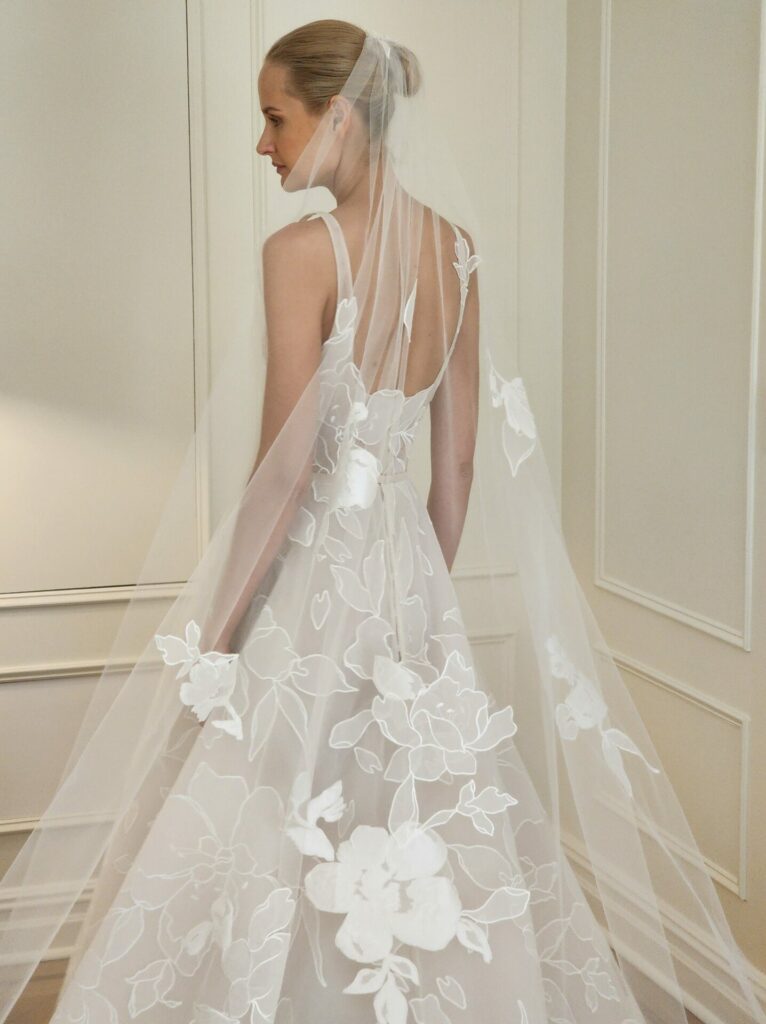 Bride in floral veil looks over shoulder.