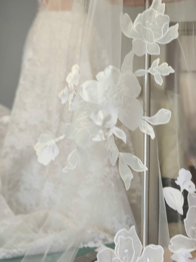 Sheer floral veil over lace wedding dress.