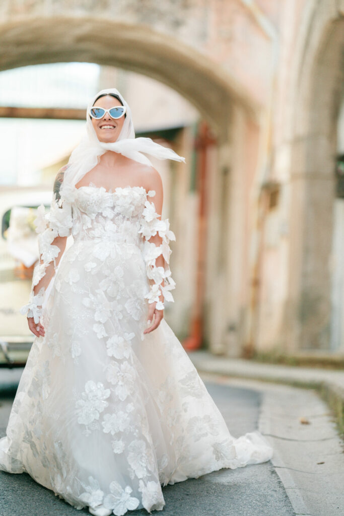 Smiling bride in white gown and sunglasses.