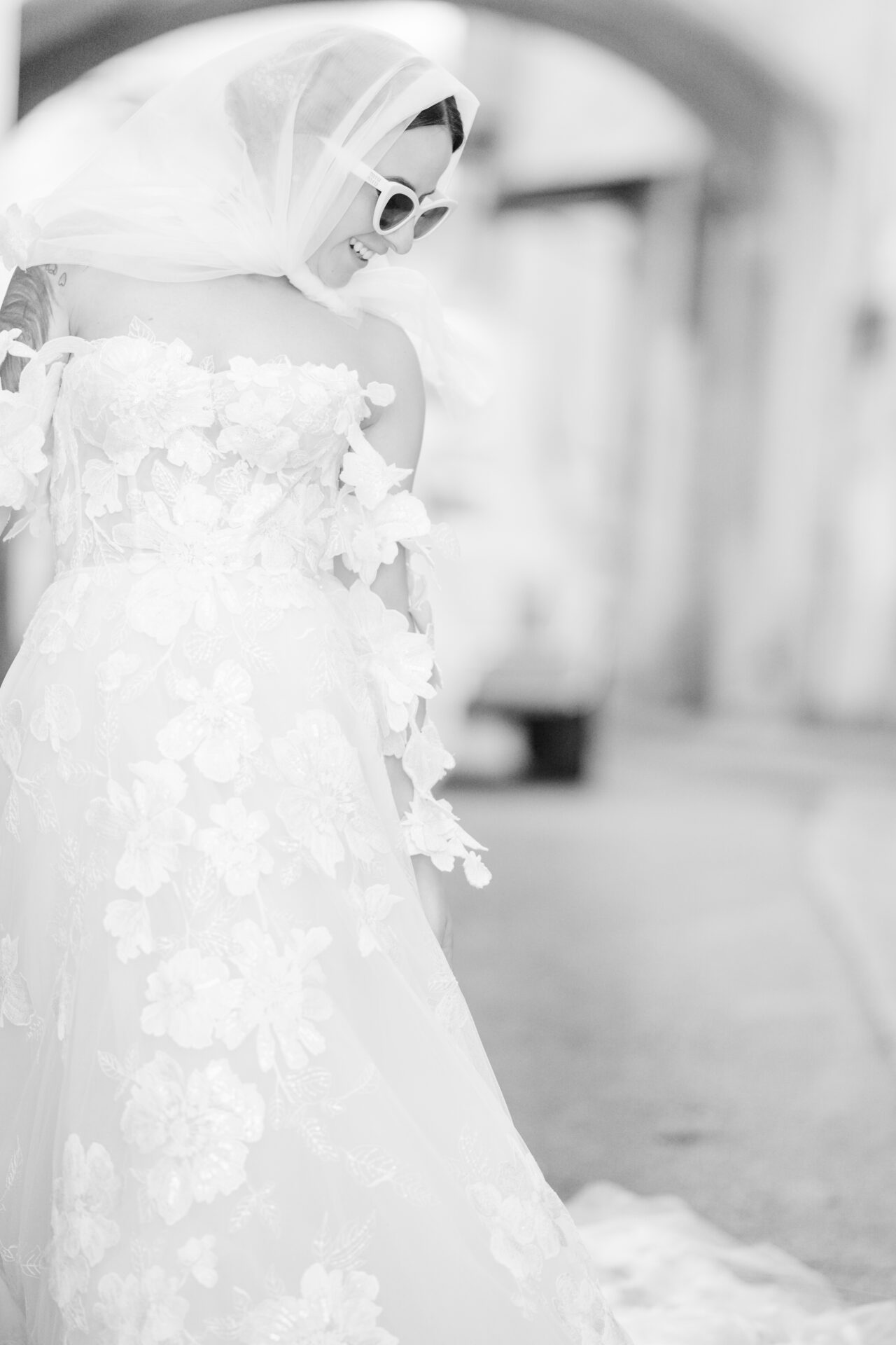 Bride in lace dress and sunglasses, outdoors.