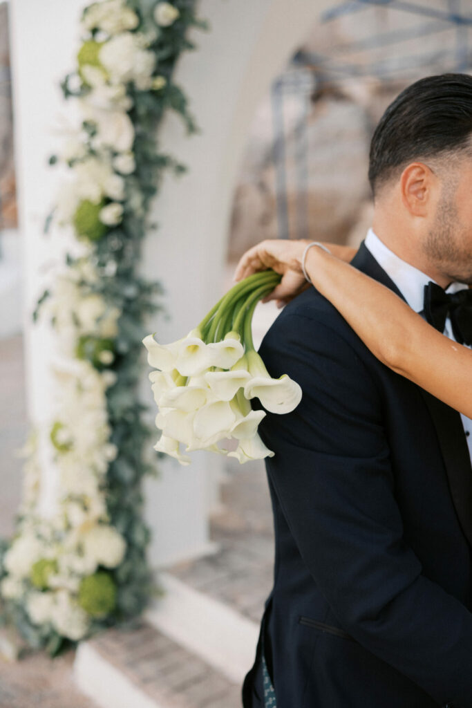 Katya Ruiz in couture gown, holding lilies, hugs groom.