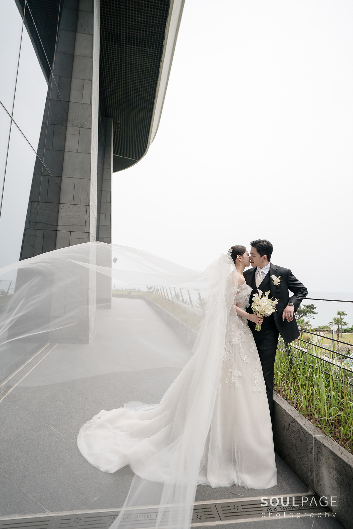 Bride and groom outside, veil flowing, affectionate gaze.