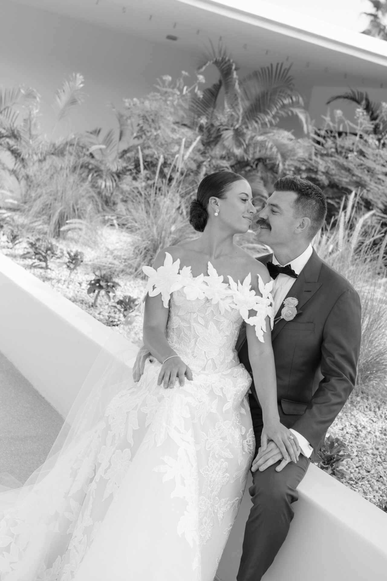 Bride and groom smiling, holding hands, black-and-white photo.
