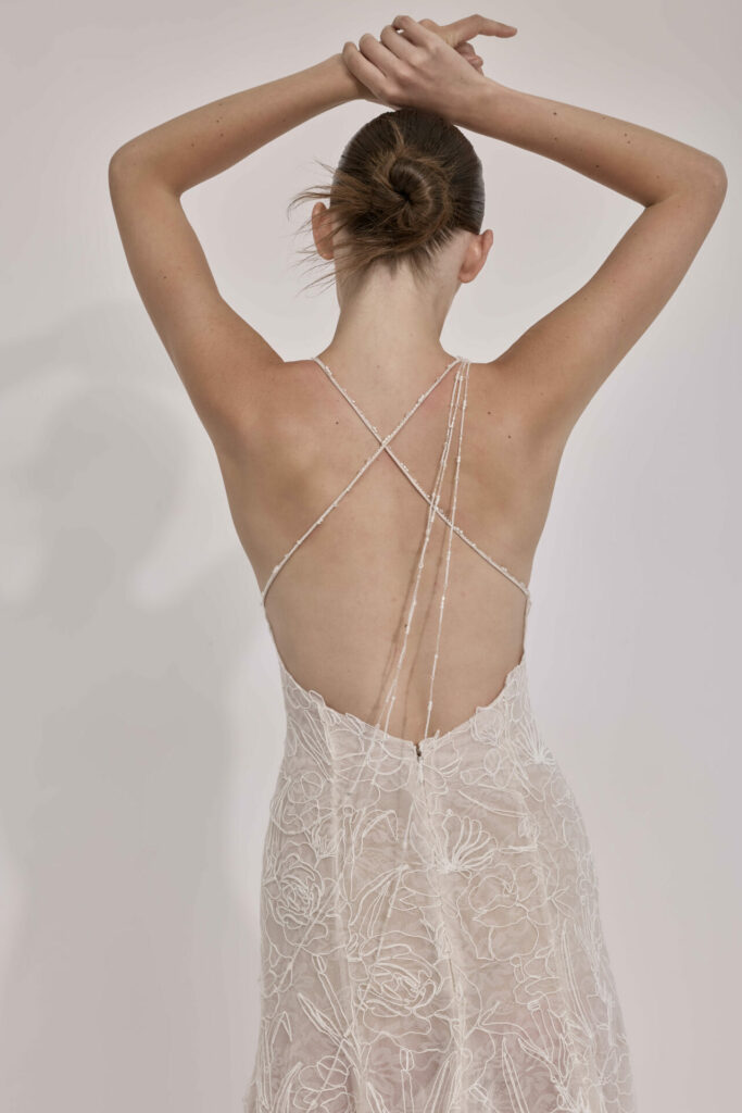 Woman in floral lace backless dress, arms raised.