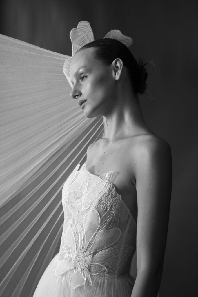 Woman in embroidered dress and veil, black-and-white.