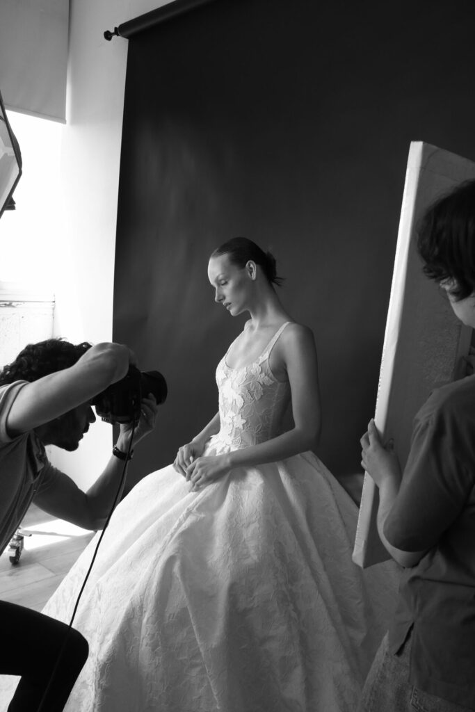 Woman in white gown poses, light reflected, monochrome.