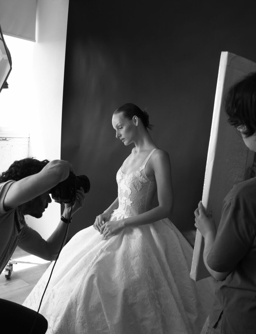 Woman in white gown poses, light reflected, monochrome.