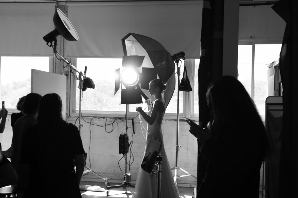 Woman in white dress in bright, bustling photo studio.