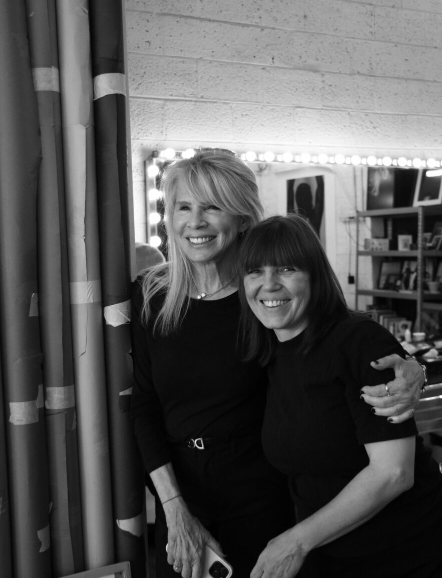 Two women smiling together in a cozy, decorated room.
