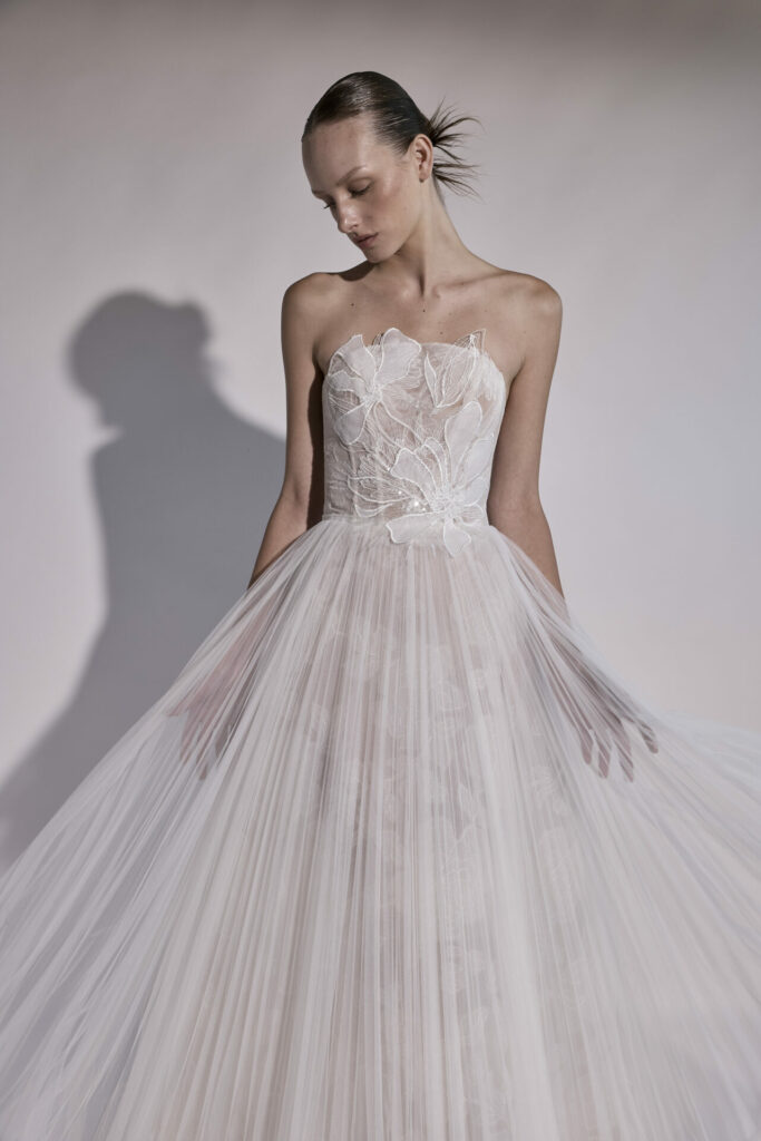 Woman in strapless white tulle gown looks down.