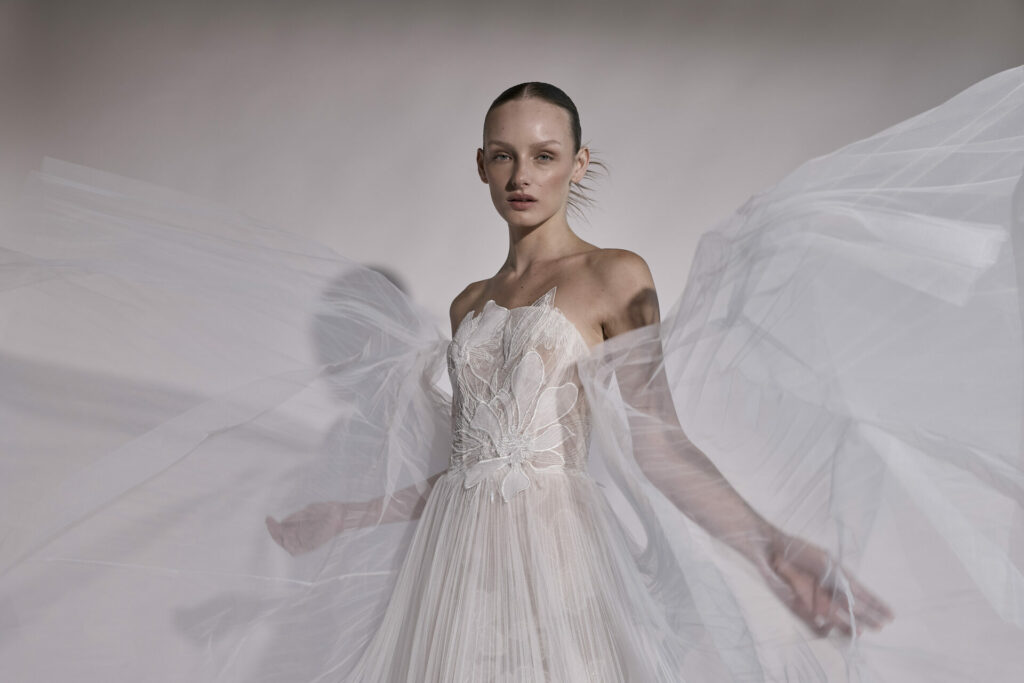 Woman in flowing white gown with dramatic tulle.