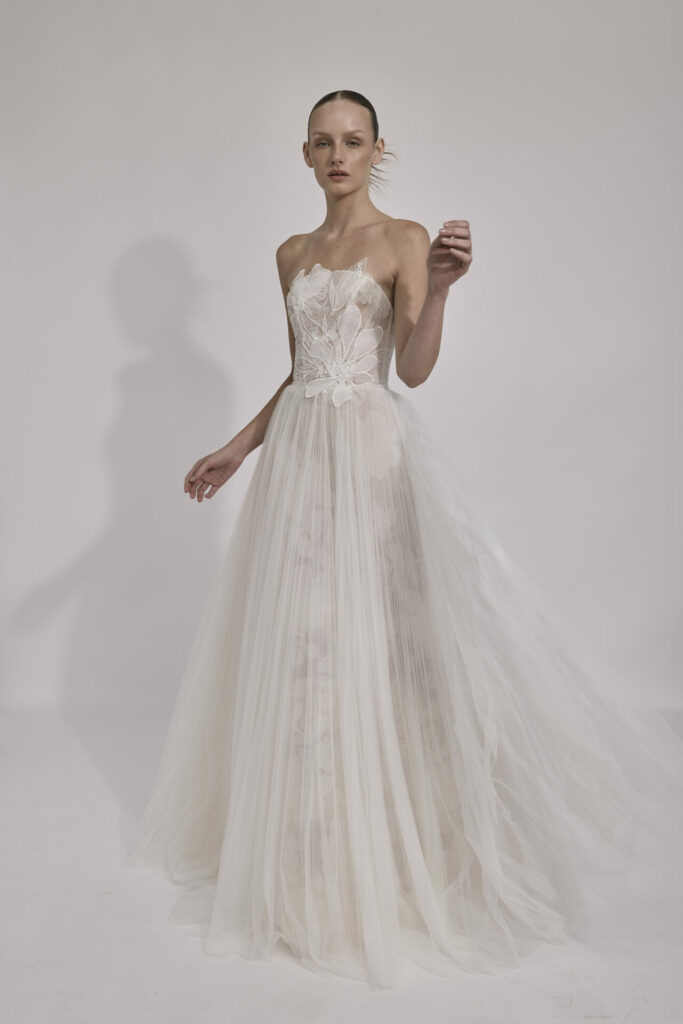 Woman in strapless white tulle wedding dress standing.
