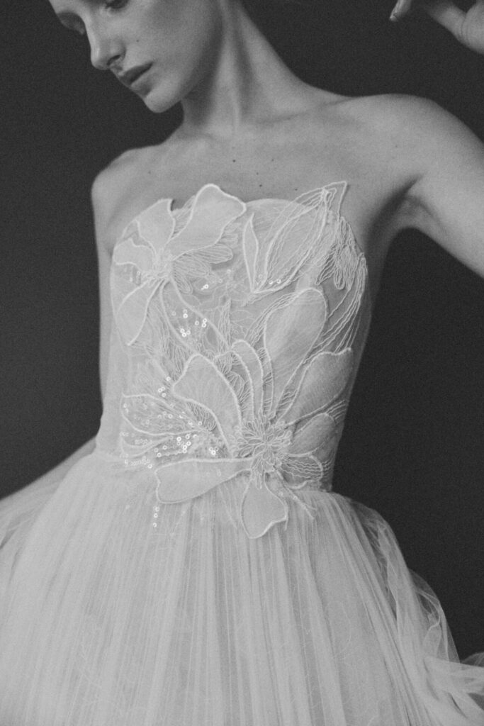 Woman in strapless floral gown poses gracefully.