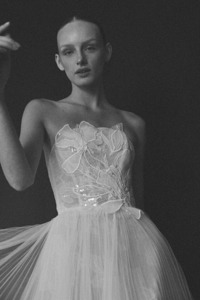 Woman in embroidered strapless gown, black and white.
