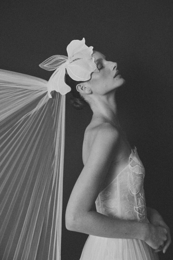 Elegant bride in sheer gown and veil, in profile.