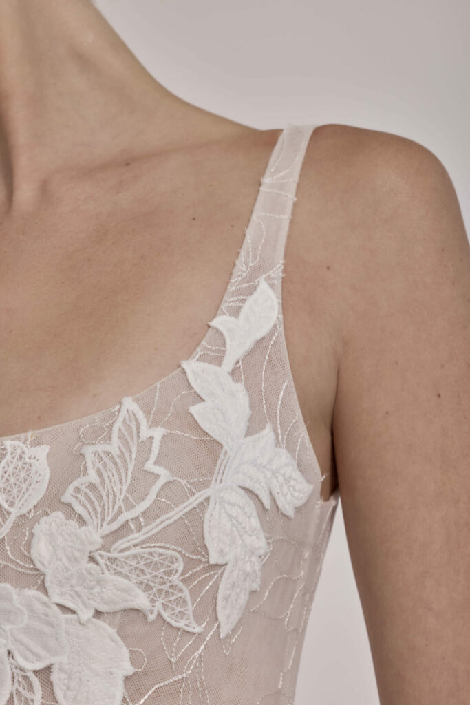 Sheer lace dress on woman's shoulder, floral details.