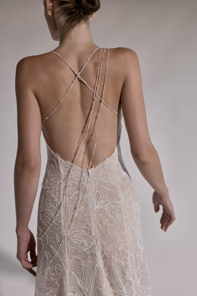 Woman in sheer embroidered dress, hair in updo.