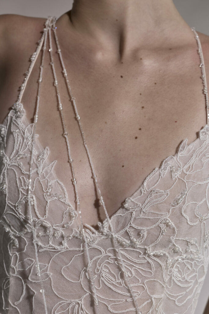 Person in sheer, white floral lace with beaded straps.