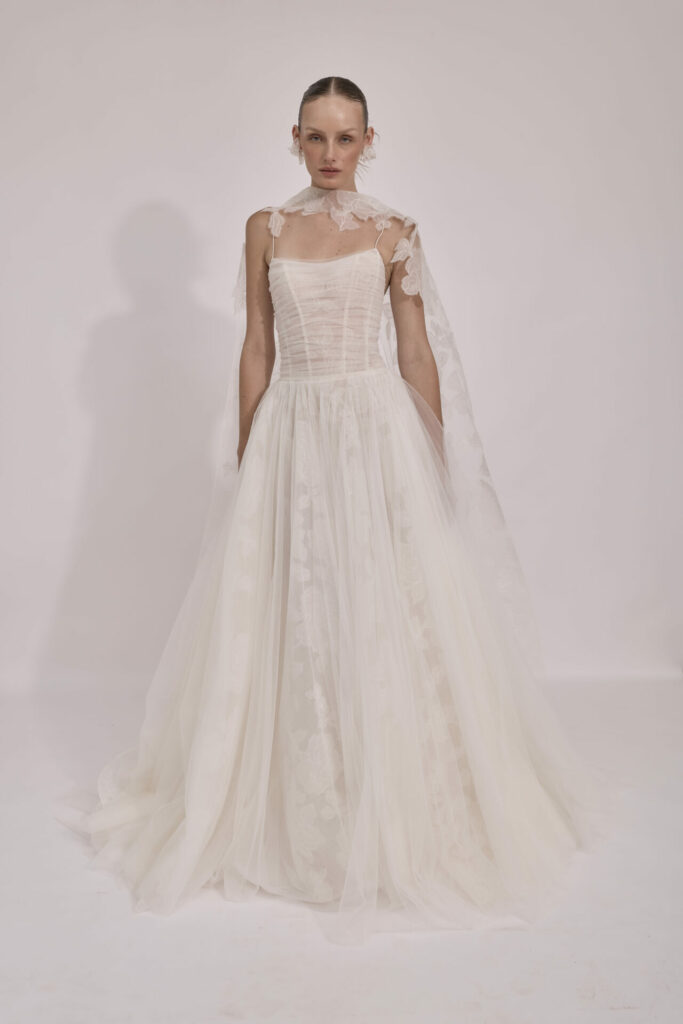 Woman in strapless white lace wedding gown and cape.