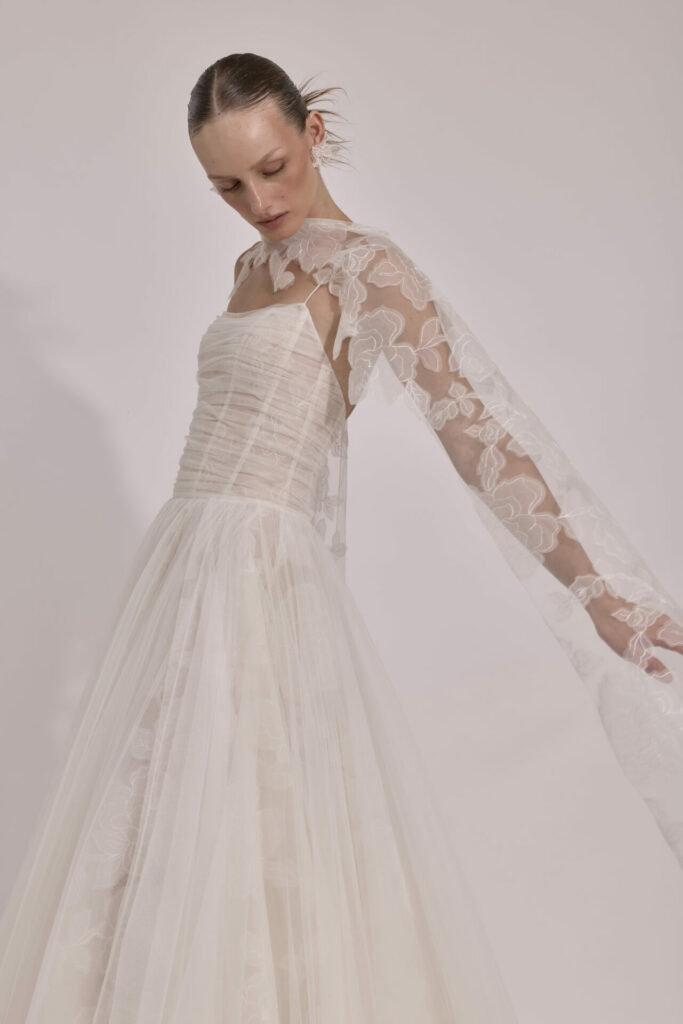 Woman in strapless lace wedding dress looks down serenely.