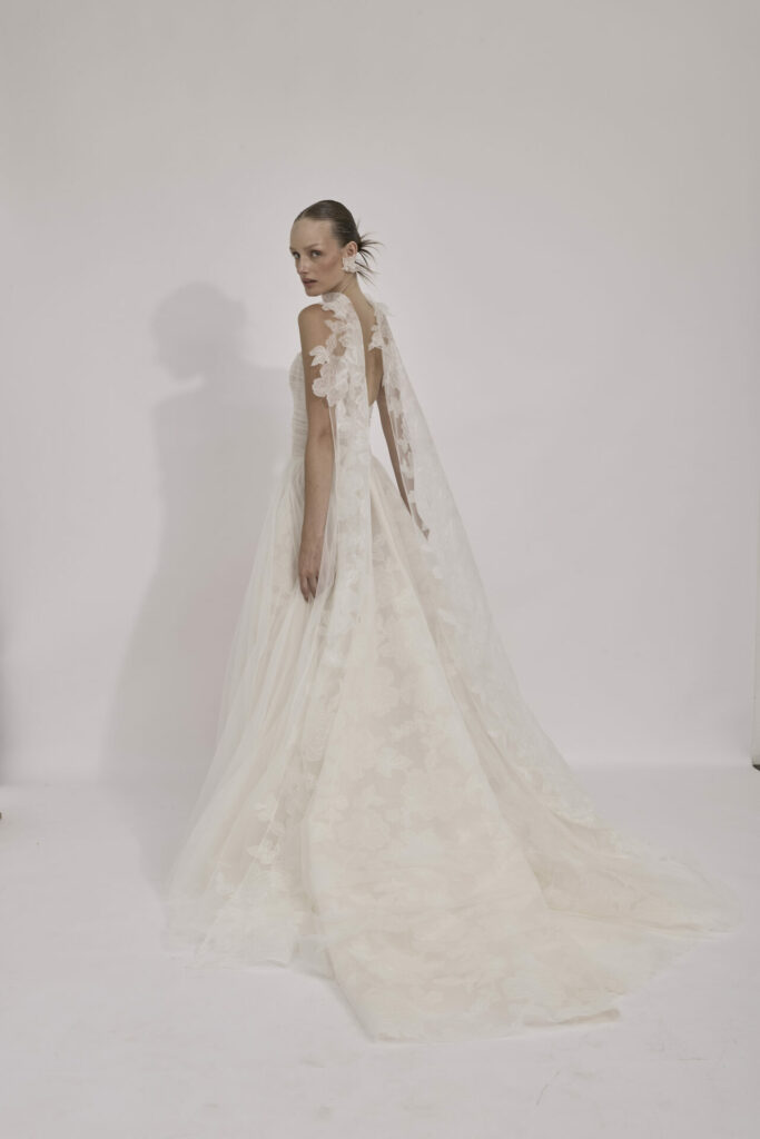 Woman in white gown with lace cape, posing.