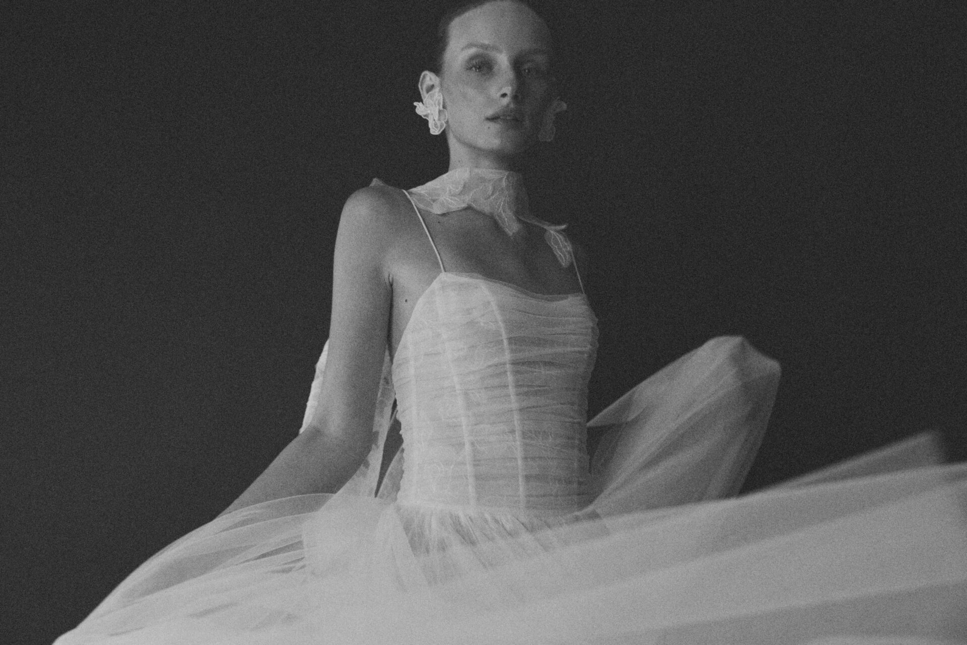 Woman in sheer white dress, floral accessory, black and white.
