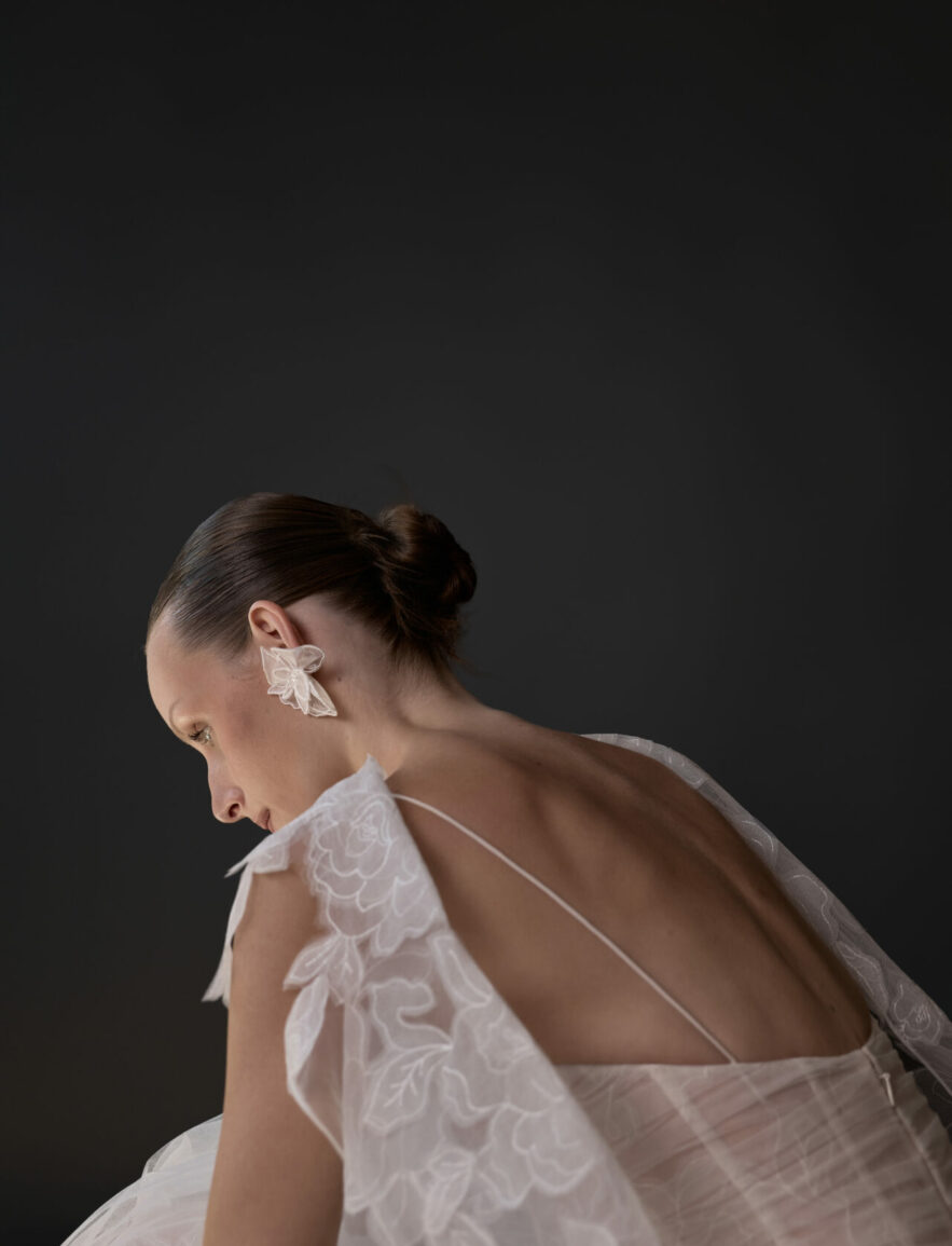 Woman in sheer white floral dress, back turned.
