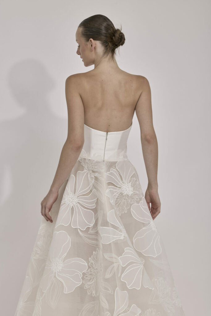 Woman in white strapless dress poses back to camera.