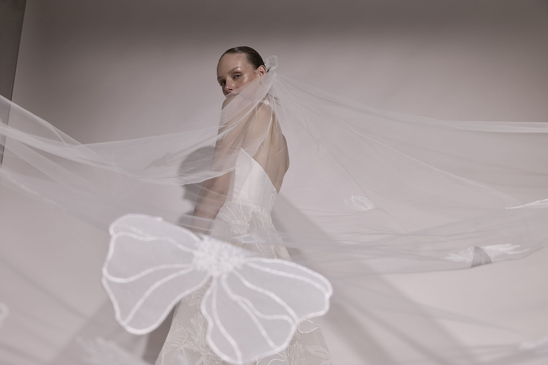 Bride in strapless gown with bow-embroidered veil.