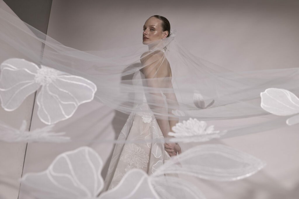Bride in sheer floral veil and white gown, 2026 trend.