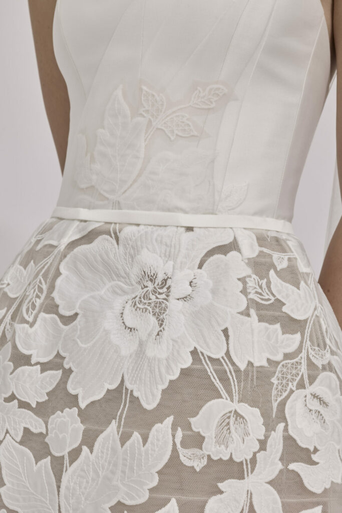 White dress close-up with floral embroidery and lace.
