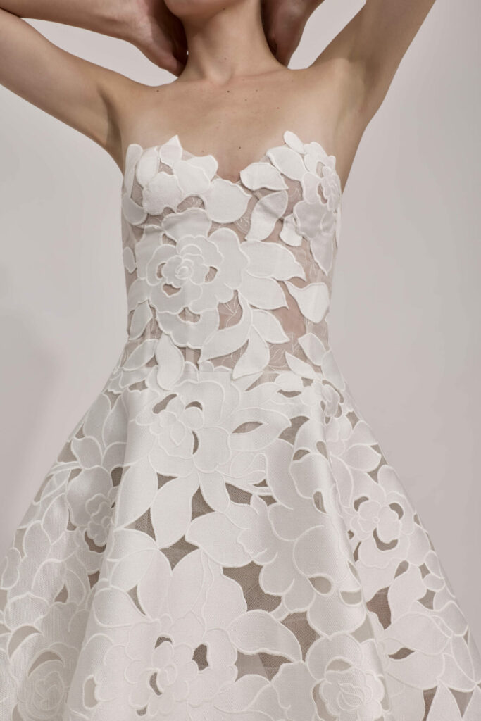 Woman in strapless white lace dress, arms raised.