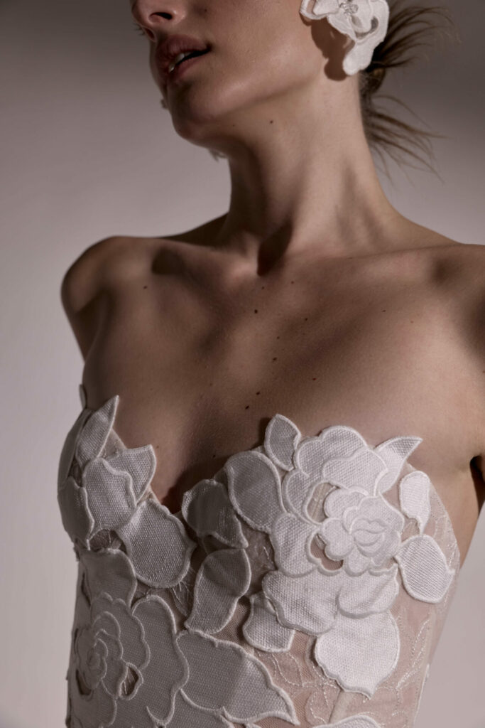 Woman in strapless dress with white floral accents.