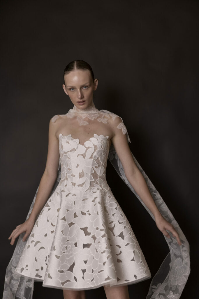 Woman in white lace dress with sheer cape.