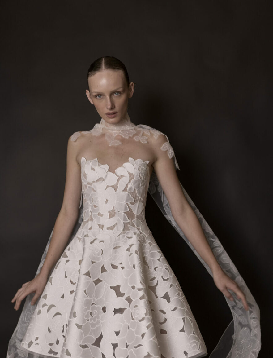 Woman in white lace dress with sheer cape.