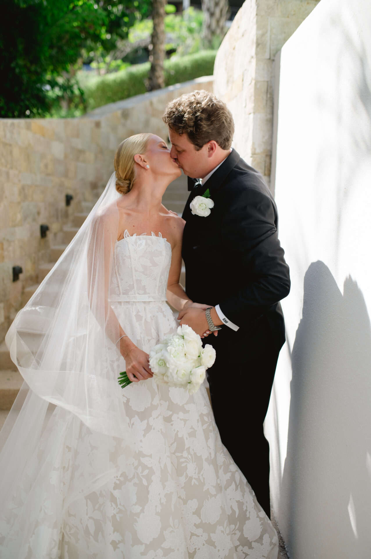 Bride and groom kiss outdoors on wedding day.