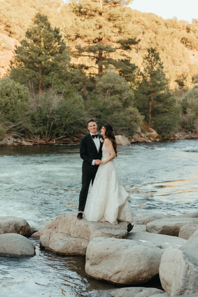 Bride and groom holding hands by river.