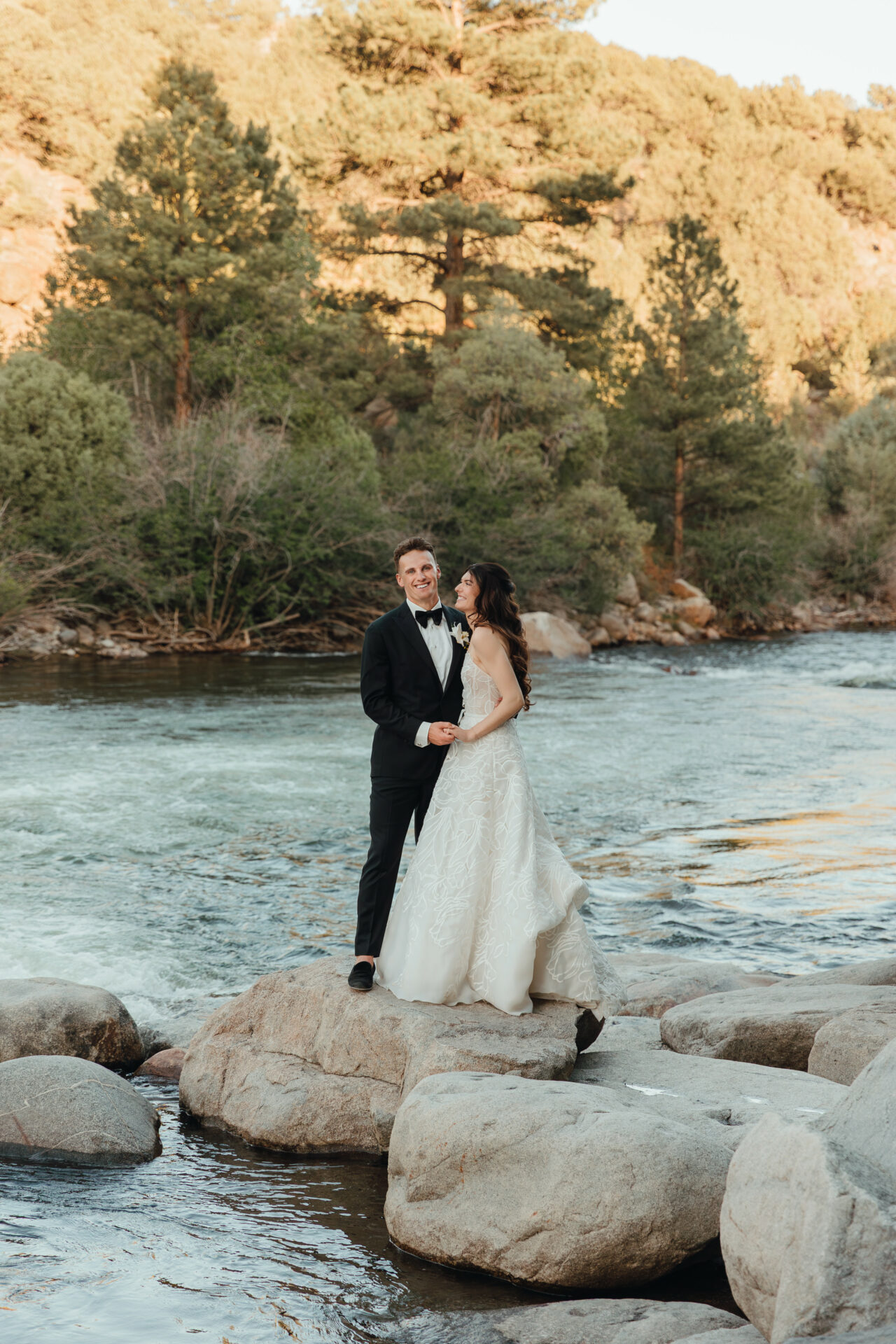 Bride and groom holding hands by river.