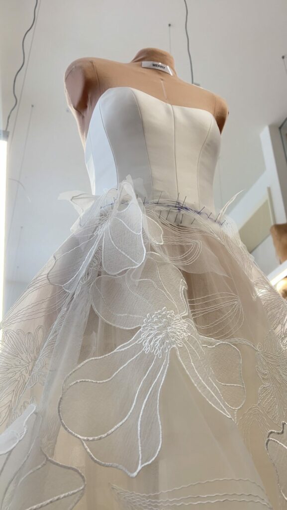 Mannequin in strapless white dress with floral embroidery.
