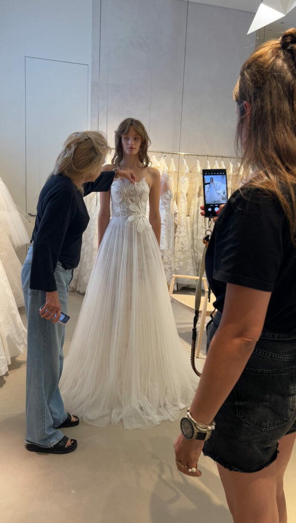 Bride in white tulle gown adjusted, photo taken.