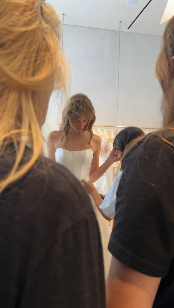 Woman in white dress assisted, two blondes in foreground.