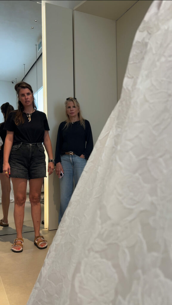 Two women indoors, textured white fabric evokes elegance.