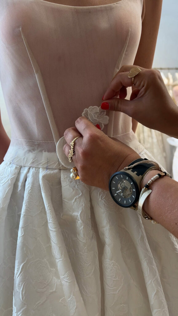 Hands adjust flower on sheer strapless gown.