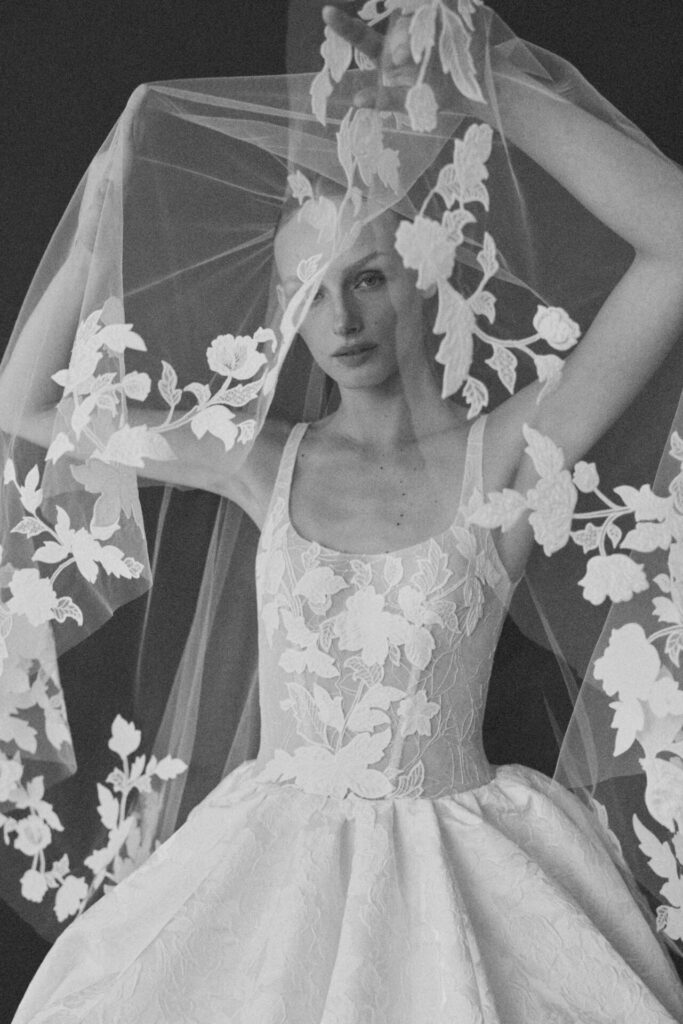 Woman with embroidered veil partially covering face.