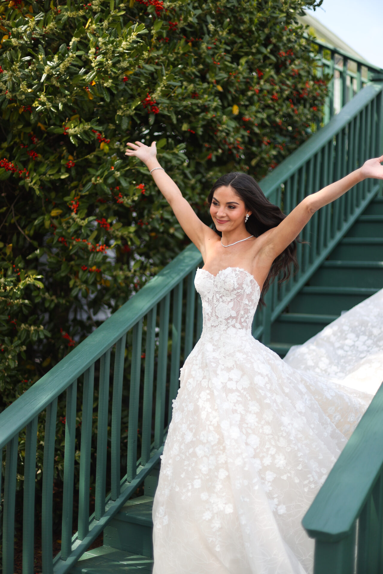 Joyful bride in lace gown on green stairs, greenery.