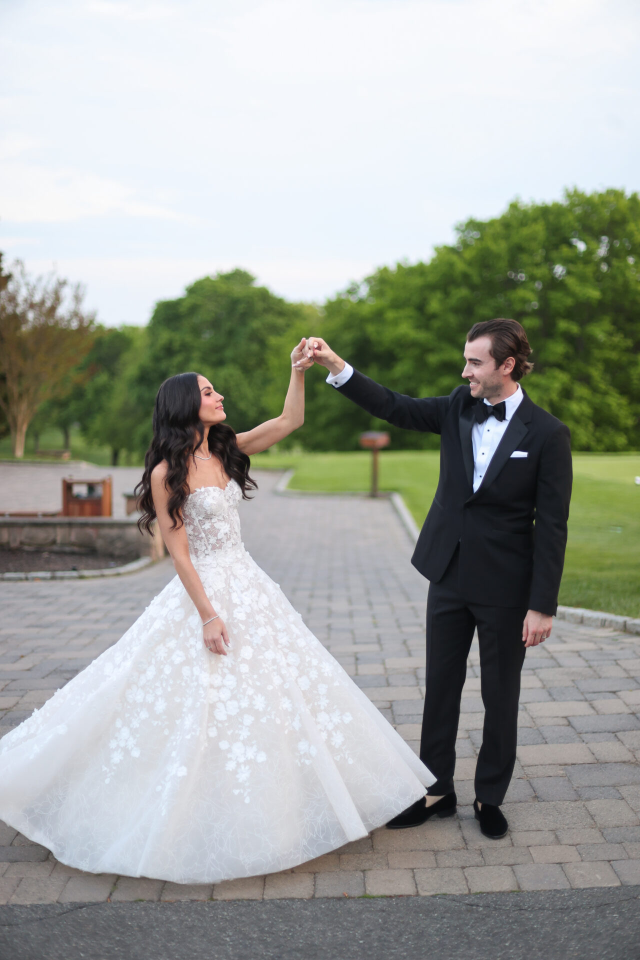 Bride and groom dance outside on a path.