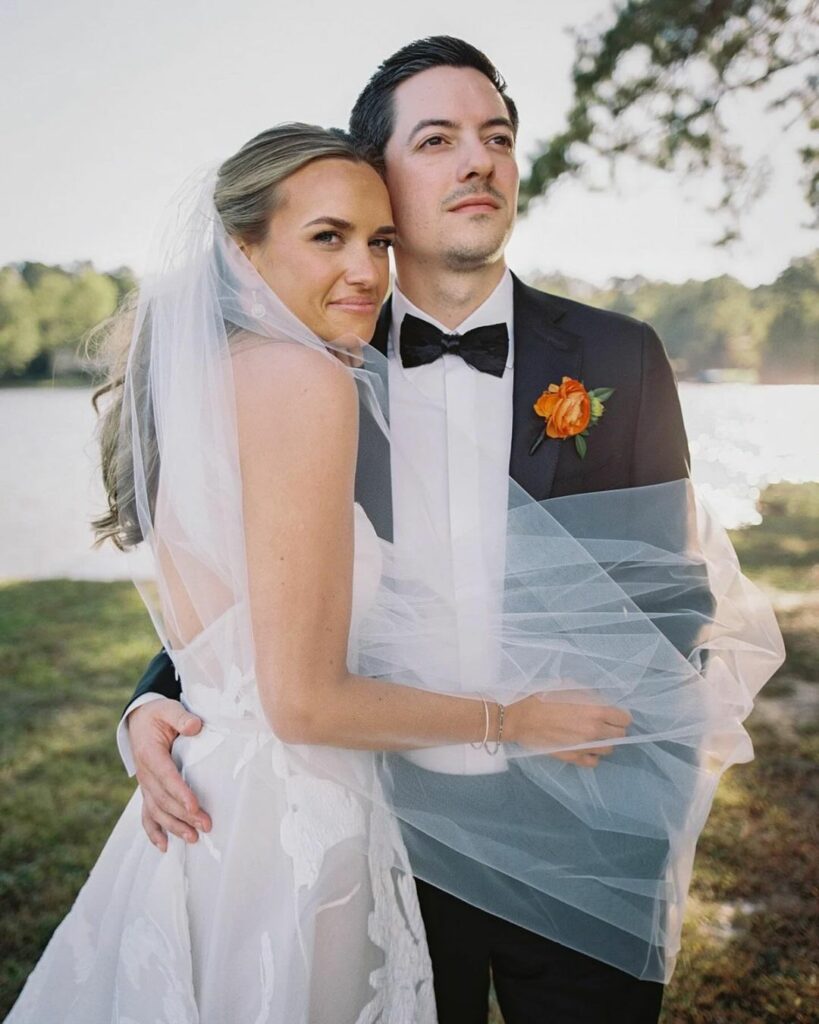Bride Katya Ruiz and groom embrace lakeside, smiling.