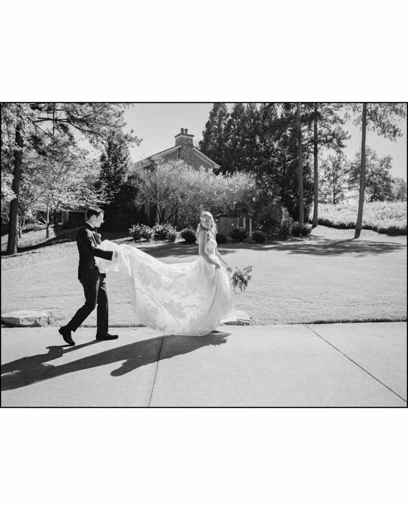 Bride in Mira Zwillinger gown walks outside with groom.