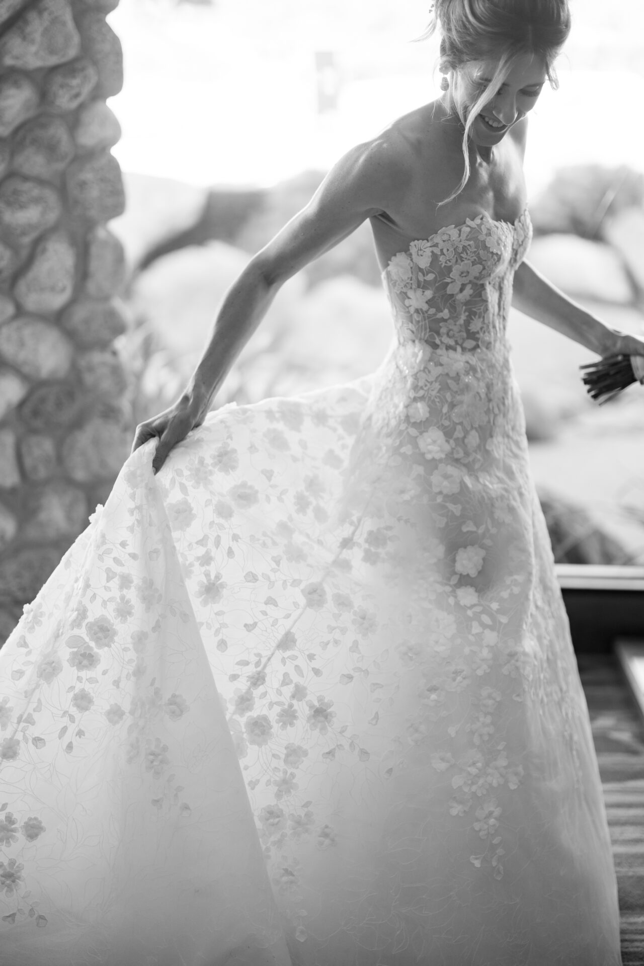 Bride twirling in lace gown, black and white scene.