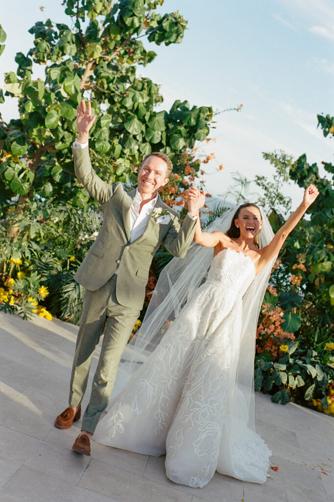 Happy wedding couple celebrates outdoors amid greenery.